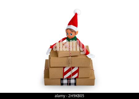 Christmas Elf  on a stack of gift boxes on an isolated  white background with copy space. Christmas spirit, Christmas family tradition. Stock Photo