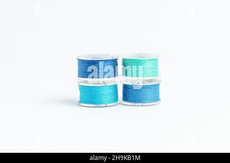 Group of mixed colourful blue spools of cotton thread displayed horizontally, isolated on white, top view Stock Photo