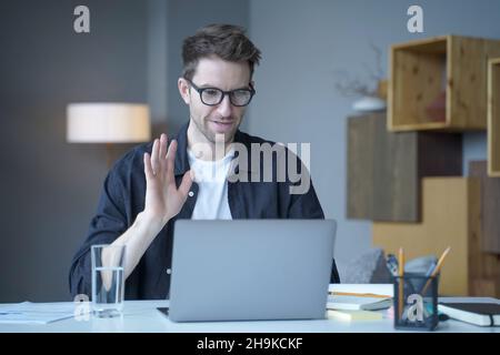 Young handsome austrian man freelancer waving hand in hello gesture during video call on laptop Stock Photo