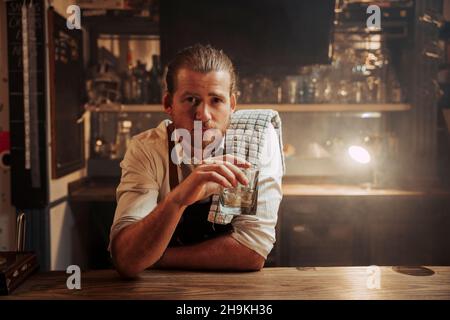Caucasian male bartender having a drink at the bar alone after work  Stock Photo