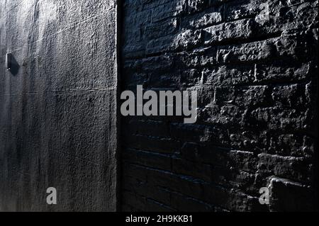 Dark concrete block and brick wall seen in perspective with light revealing the textured surface. Stock Photo
