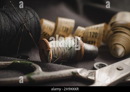 Retro tools for cutting and sewing. Needle with thread, thimble, centimeter and scissors. Tailor and seamstress Stock Photo