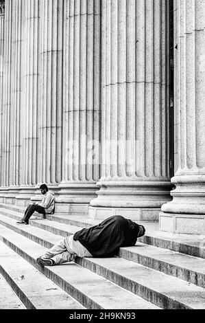 NEW YORK, USA - MAY 28, 2018: An unidentified man is sleeping on the steps of the United States Post Office in New York City. Stock Photo