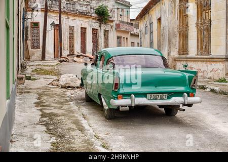 REGLA, CUBA - DECEMBER 22, 2019: A vintage green taxi is parked on a desolate and empty side street in the town or Regla near Havana in Cuba. Stock Photo