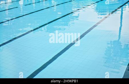 Calm water on empty swimming pool, dark lanes marks visible floor Stock Photo