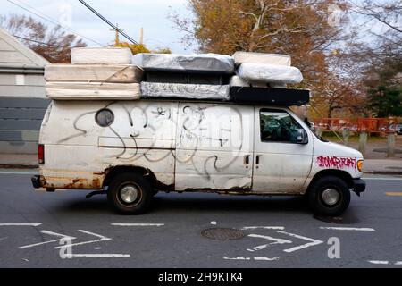 A van transports used mattresses found in the trash to a place where they will be reconditioned and resold as a yellow tag, rebuilt mattress. Stock Photo