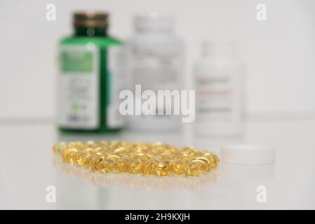 Transparent yellow pills and three white and green bottles of medicine on white background Stock Photo