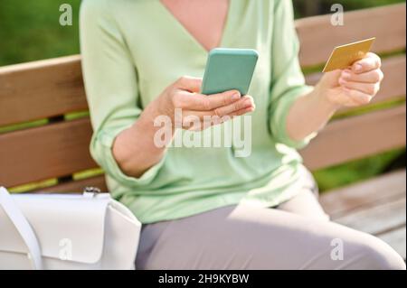 Womans hands holding smartphone and credit card Stock Photo