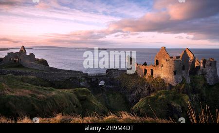 The iconic ruins of Dunluce Castle perched on a rocky outcrop on the North Antrim Coast in Northern Ireland. Stock Photo