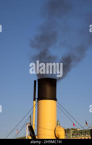 Air pollution in Stockholm. Chimney of boat with black smoke coming out of it. Climate change and carbon emission theme. Stock Photo