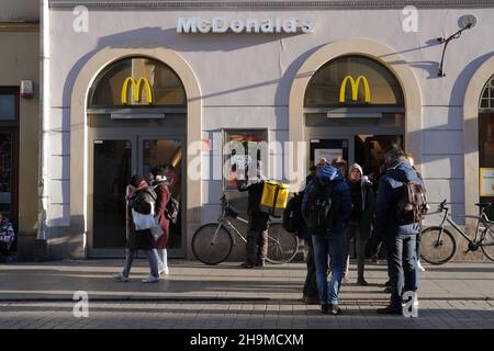 McDonalds in Krakow, Poland, cafe window with people inside, street sidewalk with people, People coming in McDonalds, crowds near McDonalds Stock Photo