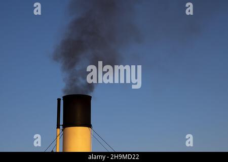 Air pollution in Stockholm. Chimney of boat with black smoke coming out of it. Climate change and carbon emission theme. Stock Photo