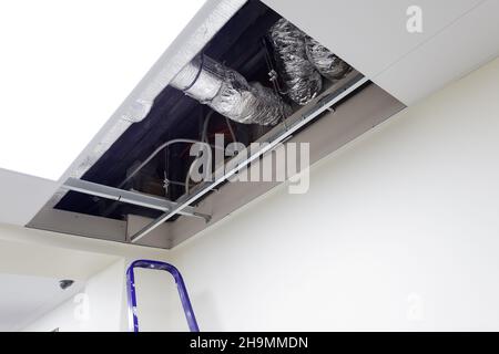 open stretch ceiling for repairing lighting and signaling wiring. Maintenance of communications in the office space Stock Photo