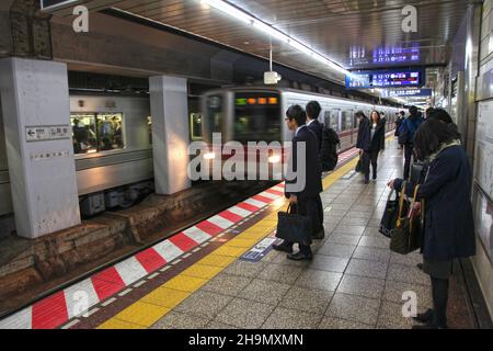 A train approaching at Tsukiji train station with many commuters on the underground platform in Tokyo, Japan. Stock Photo