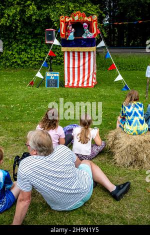 Local People Watch A Traditional Punch and Judy Show At The Nutley Village Fete, Nutley, East Sussex, UK. Stock Photo