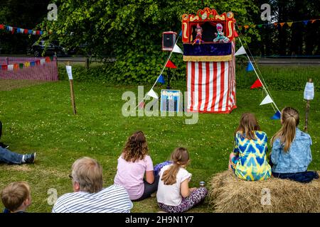 Local People Watch A Traditional Punch and Judy Show At The Nutley Village Fete, Nutley, East Sussex, UK. Stock Photo