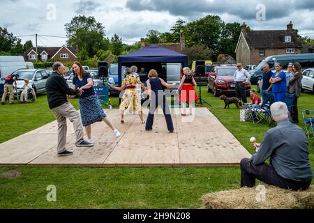 A Man Eats An Ice Cream Whilst Watching Local People Dancing At The Nutley Village Fete, Nutley, East Sussex, UK. Stock Photo