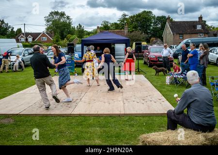 A Man Eats An Ice Cream Whilst Watching Local People Dancing At The Nutley Village Fete, Nutley, East Sussex, UK. Stock Photo