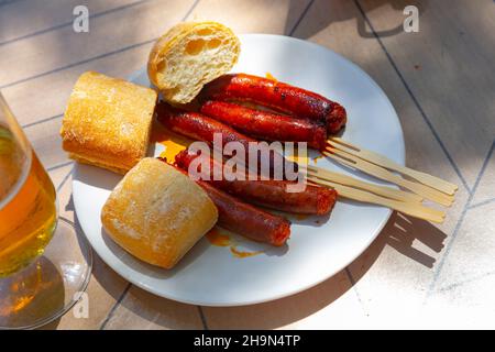 Mildly spiced grilled mini sausages chistorra. Tapa from Basque Country cuisine Stock Photo