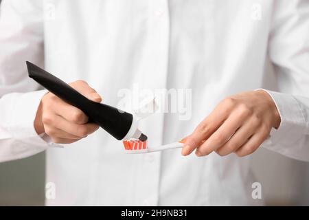 Woman applying black tooth paste onto plastic brush, closeup Stock Photo