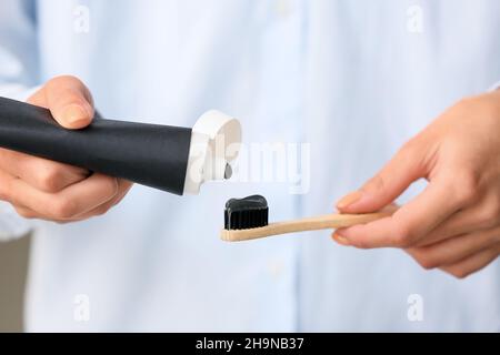 Woman applying black tooth paste onto bamboo brush, closeup Stock Photo