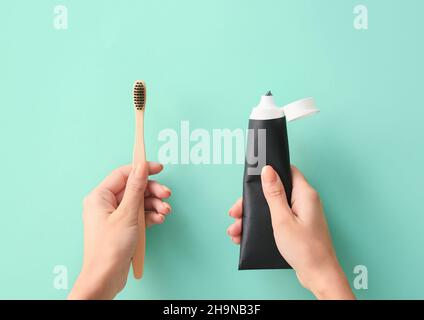 Woman with tube of black tooth paste and bamboo brush on blue background Stock Photo