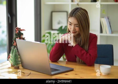 Business woman having an online meeting with strategy team via laptop computer. Female entrepreneur using computer notebook. Stock Photo