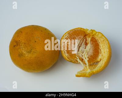 two oranges, one peeled on a white background. healthy fruit concept Stock Photo