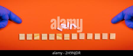 Hands in medical gloves point on wooden blocks on colored orange background with medicine pills. Concept book cover medical scientific or biological t Stock Photo