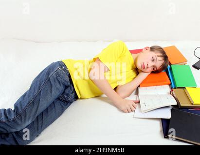 Sad and Tired Kid with the Books on the Bed Stock Photo