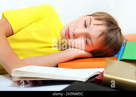 Sad and Tired Kid with the Books on the Bed Stock Photo