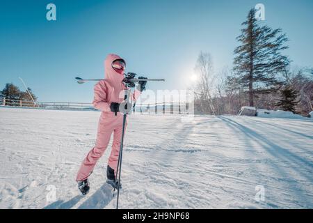 Winter Ski. Skiing portrait of woman alpine skier holdings skis wearing helmet, cool ski goggles, hardshell winter jacket and ski gloves on cold day Stock Photo