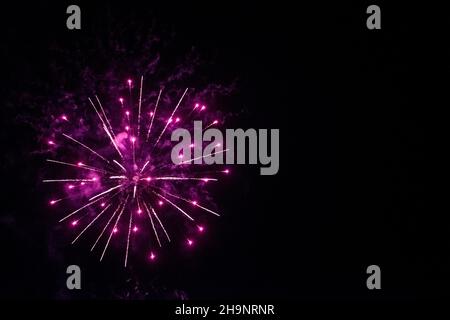 round fireworks and purple fireworks against the black sky. Christmas fireworks in the night sky. Christmas fireworks. Color of the year very peri Stock Photo