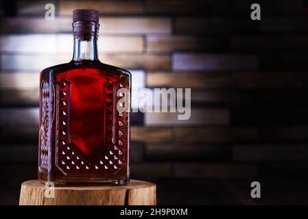 Alcohol bottle on wooden stand by brick wall. Stock Photo