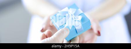 Man hand passes gift box to woman Stock Photo