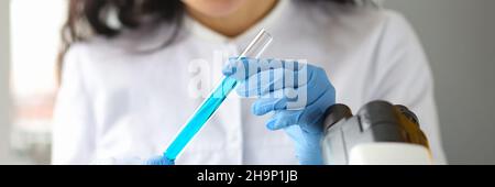 Scientist hands in gloves holds test tube with blue liquid in laboratory Stock Photo