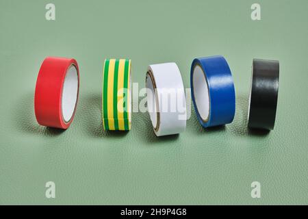 Set of multicolored insulating adhesive tape on green background Stock Photo