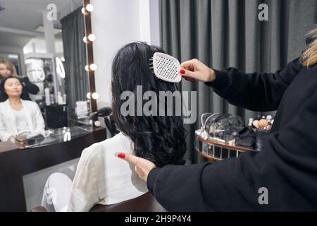 Charming woman looking to the mirror while getting beauty procedure in salon Stock Photo