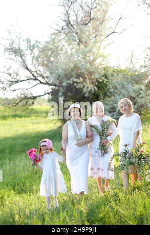 European granny hugging daughters and granddaughters, wearing white