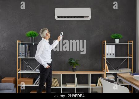 Man turn on modern conditioner in home living room Stock Photo