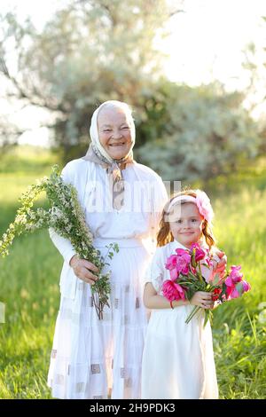 Smiling granny hugging daughters and granddaughters, wearing white