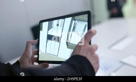 Virtual drawing of house on tablet. Stock. Businessman holding tablet with virtual reality project at home in boardroom. Digital 3D model of real esta Stock Photo