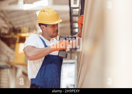 Male worker using cordless electric drill at construction site Stock Photo