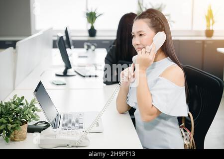 Business employee in phone calling to help support customer in office happy smile to service. Stock Photo
