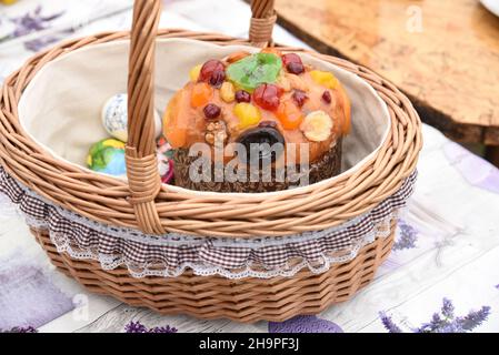 Decorated beautiful wicker Easter basket with Easter cake, painted eggs, treat Stock Photo