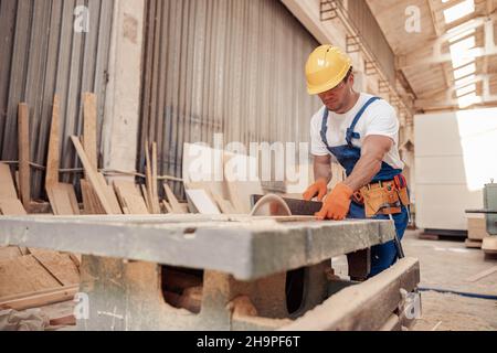 Male builder using industrial woodworking equipment in workshop Stock Photo