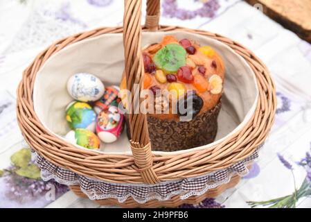 Decorated beautiful wicker Easter basket with Easter cake, painted eggs, treat Stock Photo
