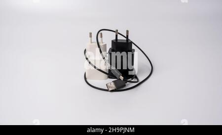 This is a black and white smartphone charger on a white background. It has a rectangular shape with rounded corners and a rounded back. Stock Photo