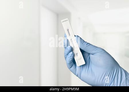 Gloved hand holding a negative rapid test device for COVID-19 in the hospital. Stock Photo