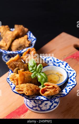Asian food concept Homemade deep fried Wonton with plum sauce in asia style pedestal tray on wooden board with copy space Stock Photo